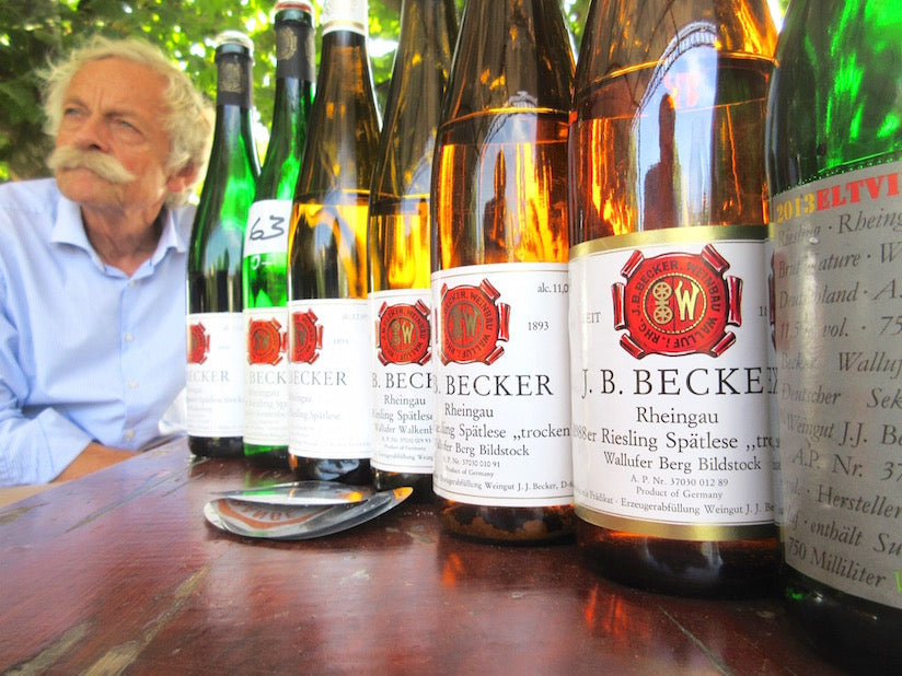 HaJo Becker seated beside a lineup of J.B. Becker Riesling bottles
